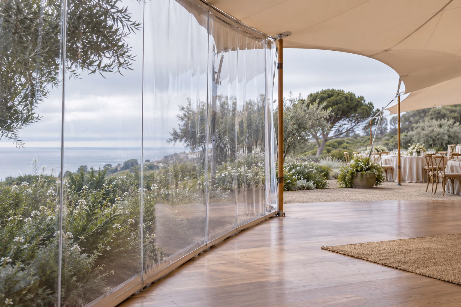 Illustration of clear tent sidewalls and an open entrance overlooking a coastal garden.