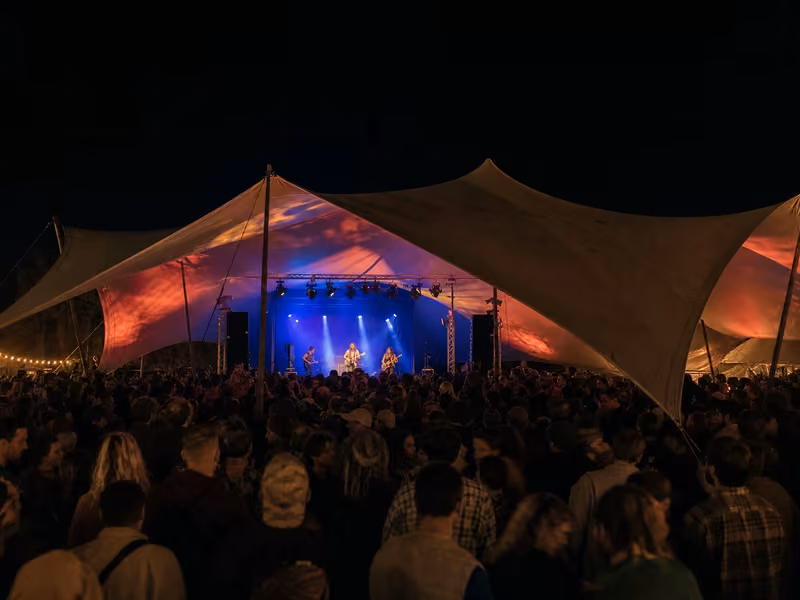 Stretch tent rigged over a festival stage at night