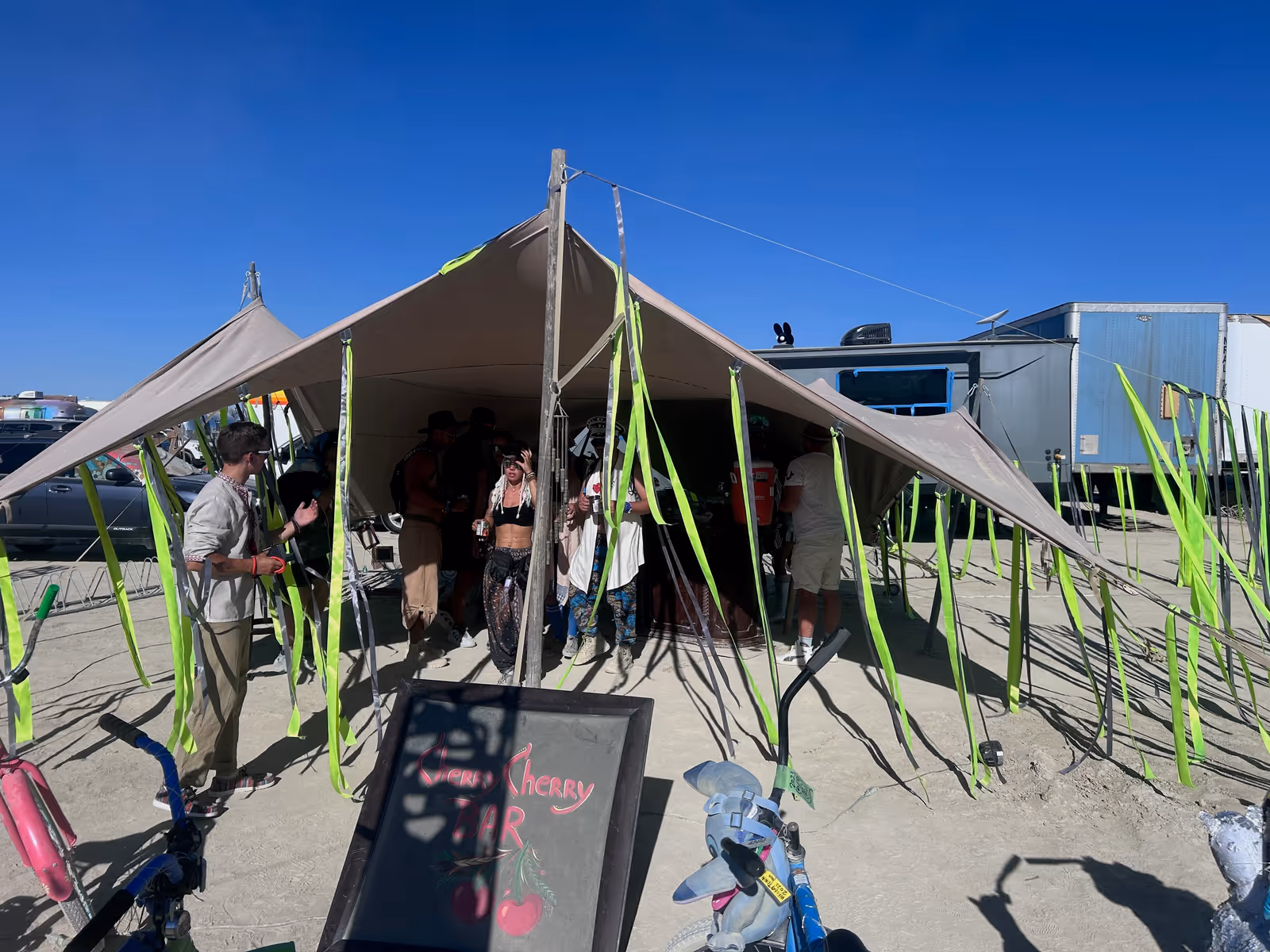 Stretch tent bar set up on the open playa at Burning Man under a clear desert sky