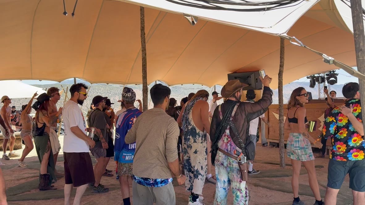 Guests dancing beneath a stretch tent at a desert music event