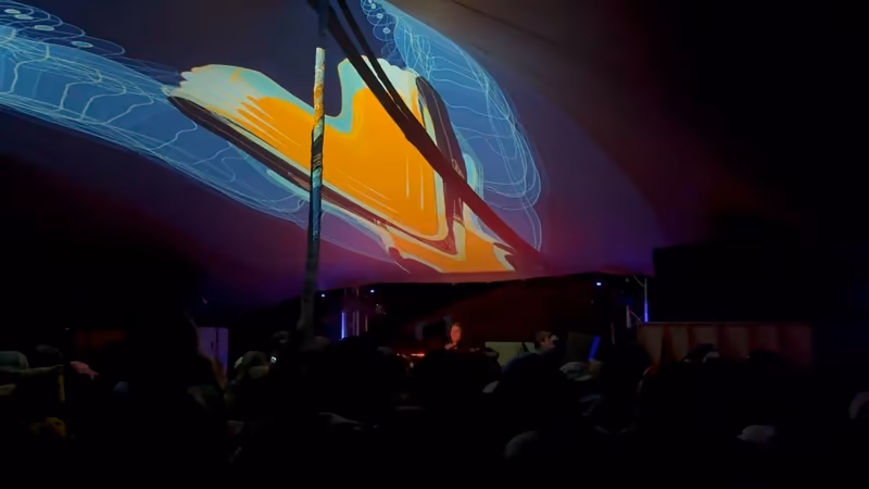 Colorful visual projection mapped across a stretch tent above a crowd