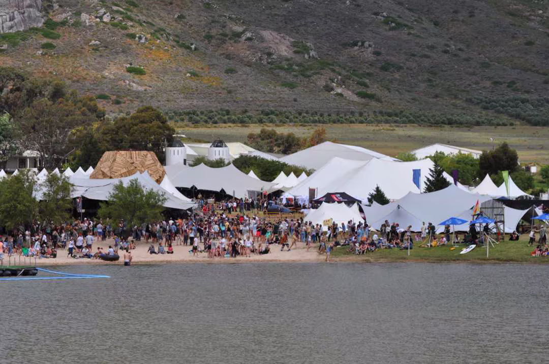 Festival crowd gathered beneath multiple linked stretch tent canopies