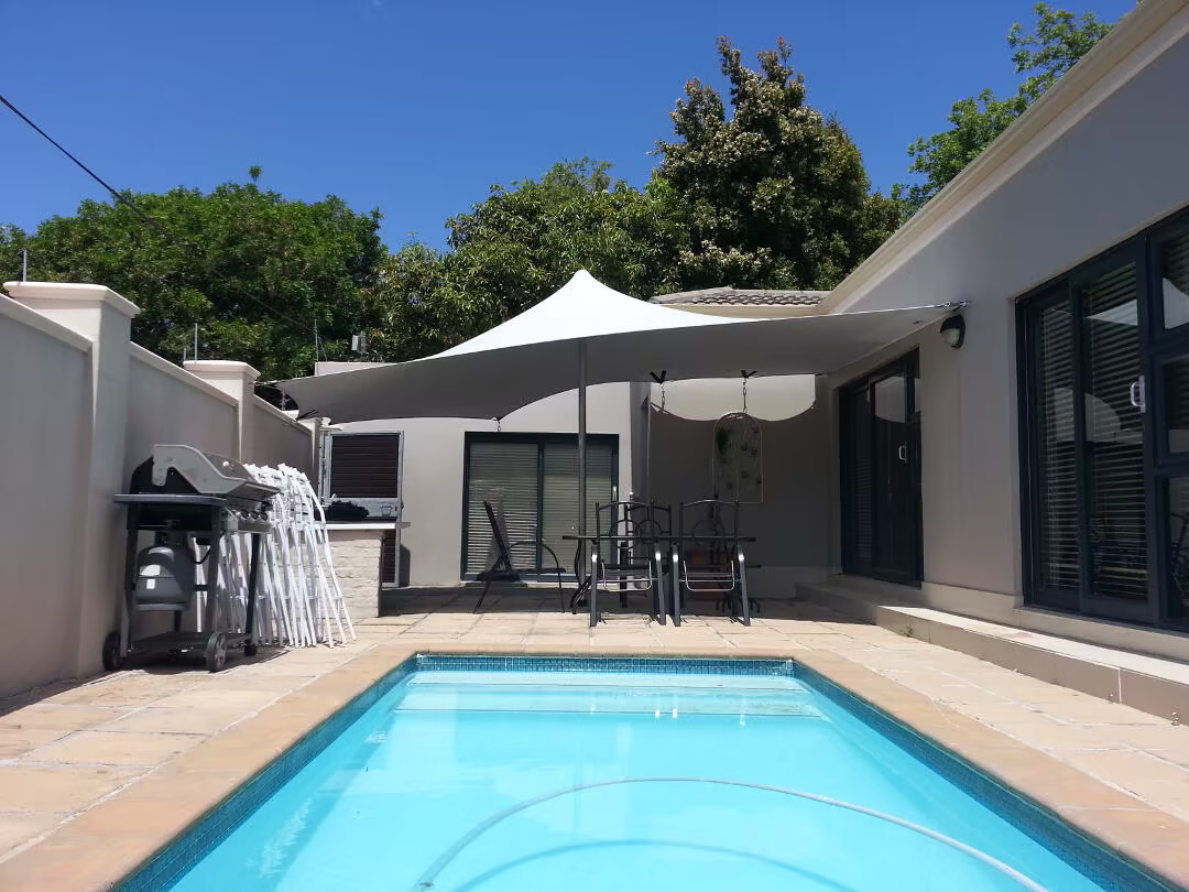 Compact white stretch tent installed beside a residential pool and patio