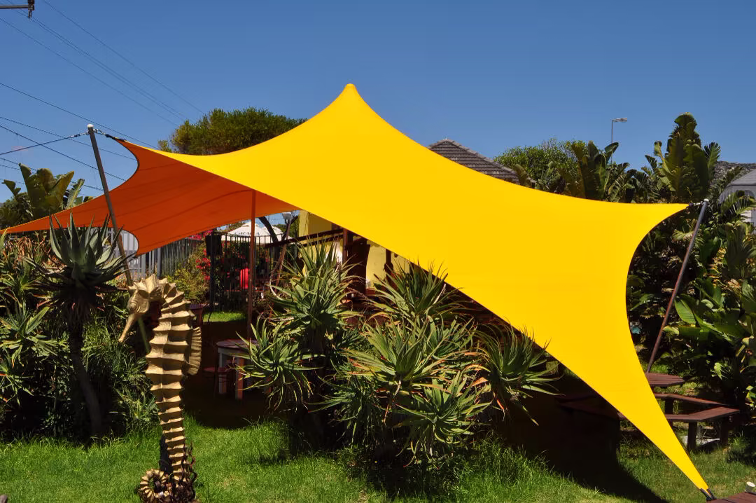 Compact yellow stretch tent installed in a garden