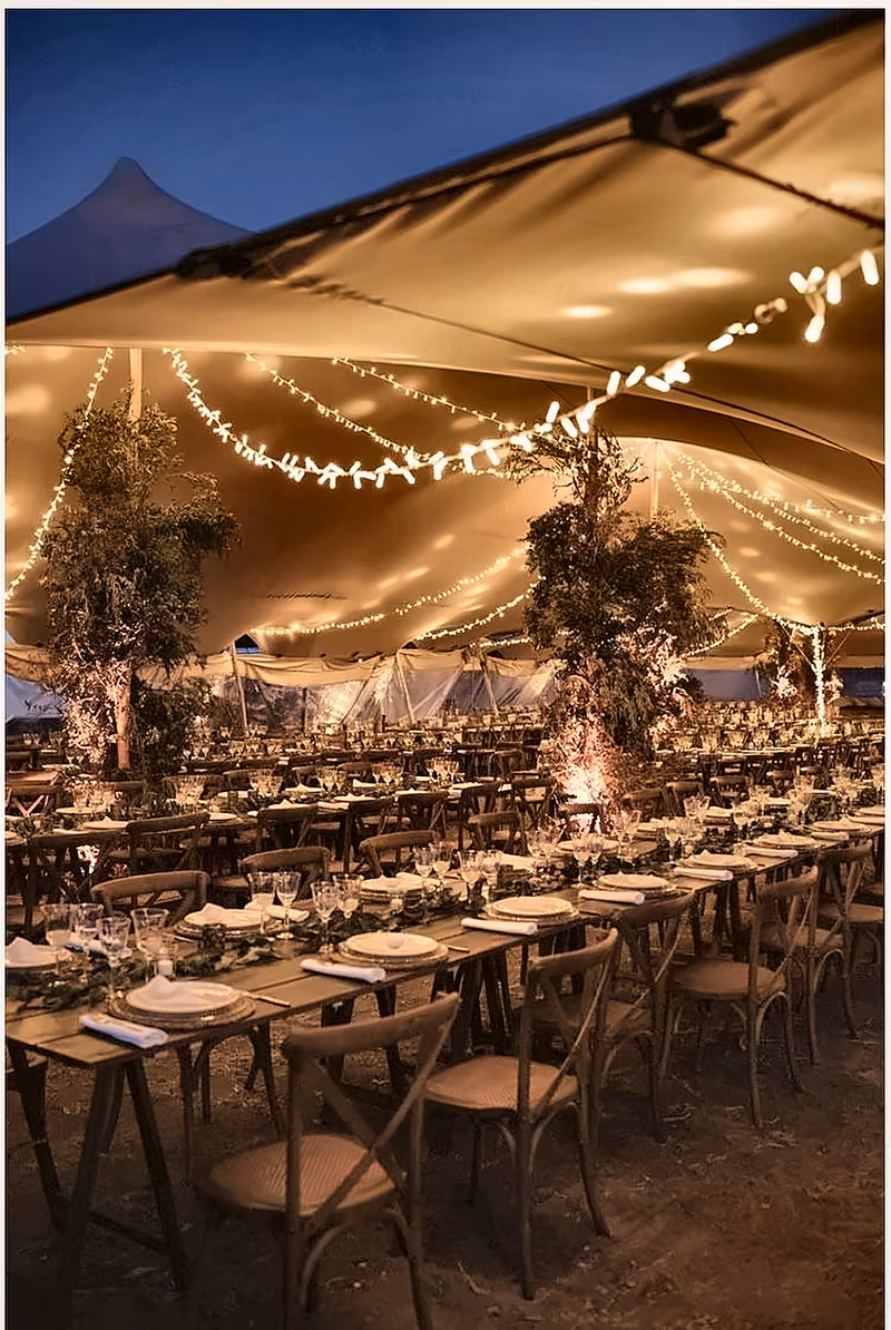 Candlelit long tables under a canopy at night