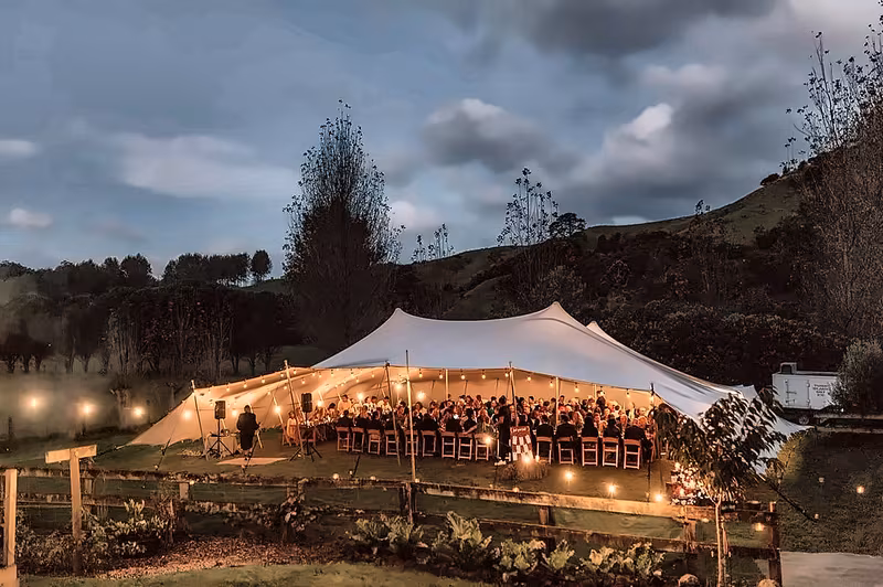 Stretch tent on a hillside meadow at dusk