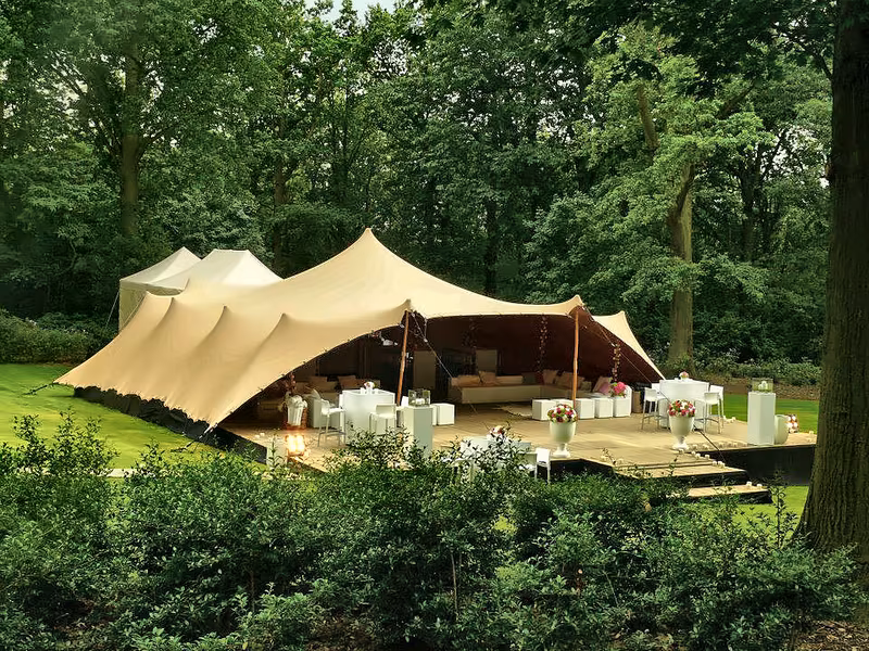 Cream stretch tent pitched in a woodland clearing