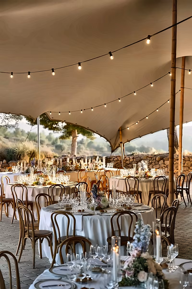 Wedding tablescape under a white canopy with festoon lighting
