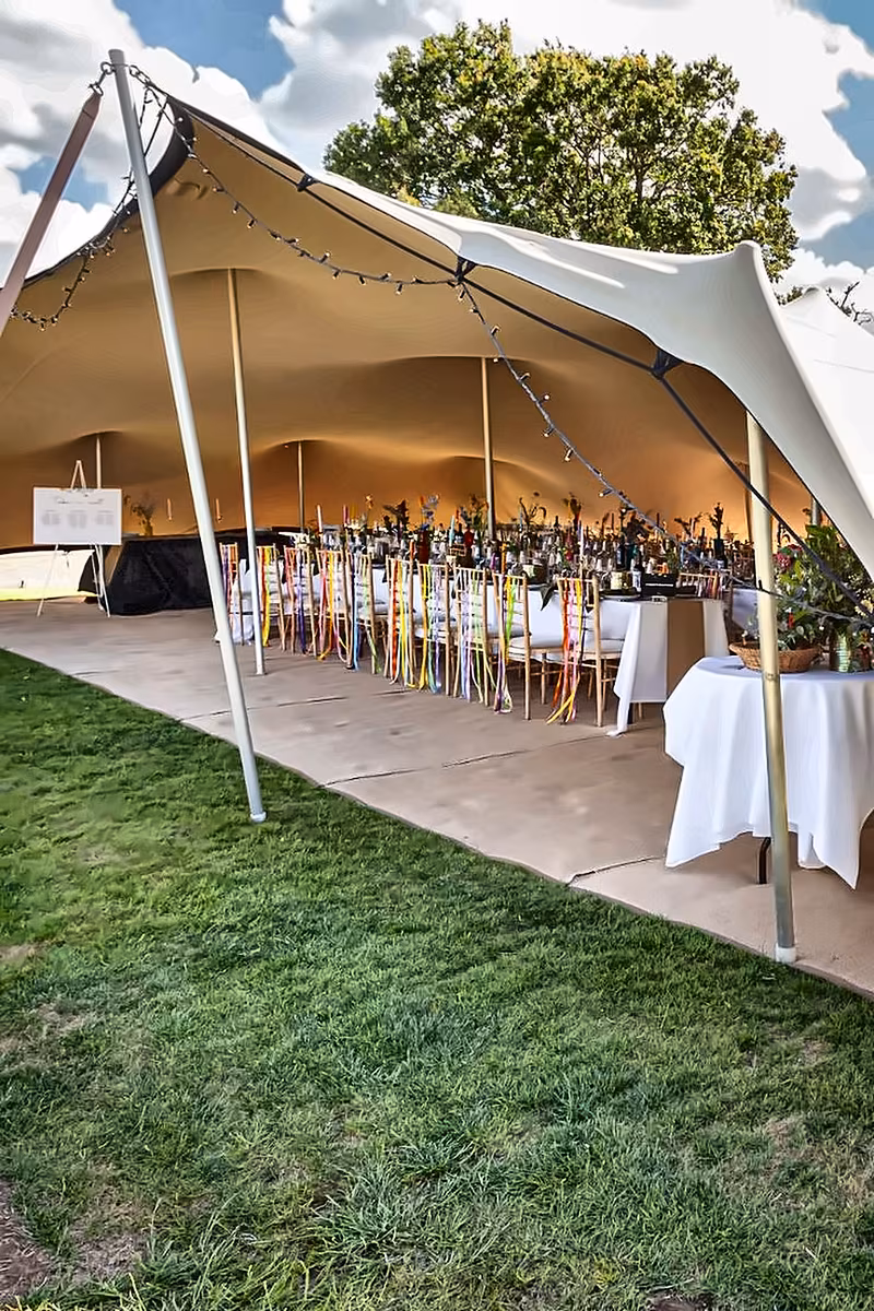 Bright stretch tent interior with bar tables and greenery