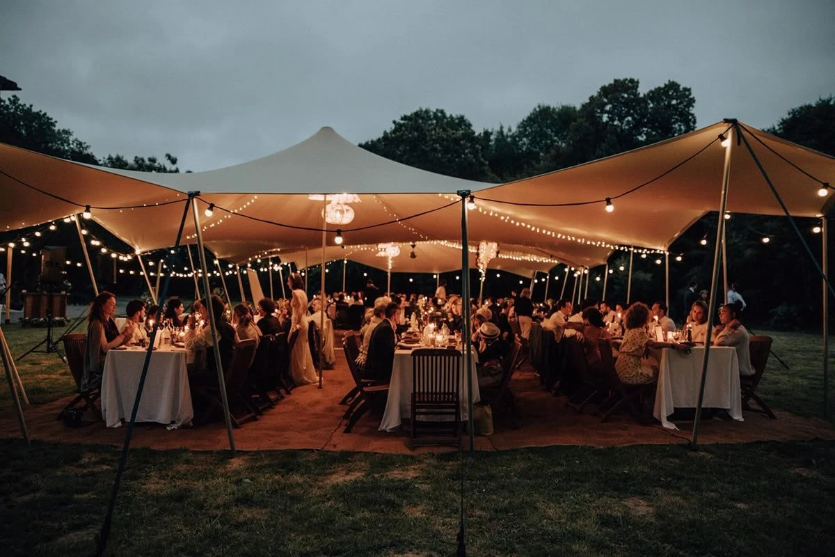 Guests dining beneath a warmly lit stretch tent