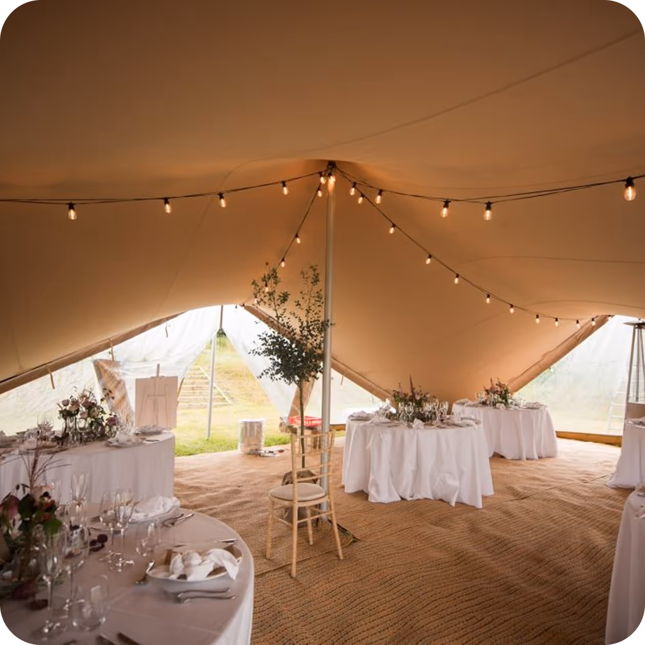 A large tent with tables and chairs set up for a wedding.