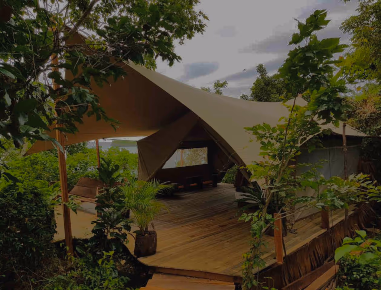 A large tent set up on a deck surrounded by trees.